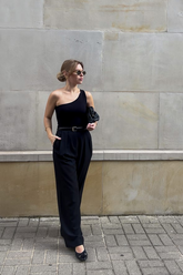 a lady in a black asymmetrical top and a pair of black pants with a belt